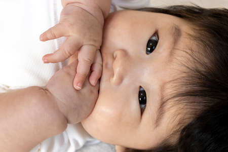 Baby's face licking hands (0 years old, 4 months old, girl)