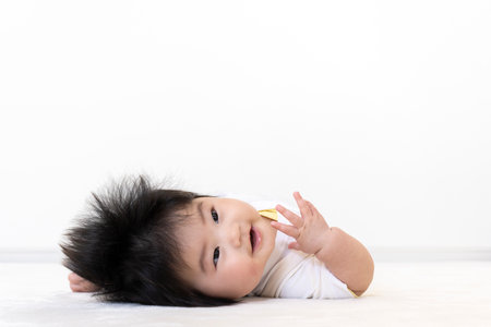 Baby lying on his back and looking at the camera (0 years old, 5 months old, girl)