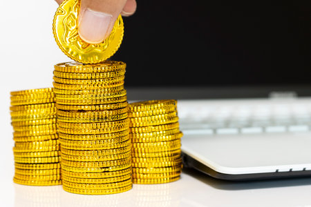 Stacked gold coins and laptops, business image