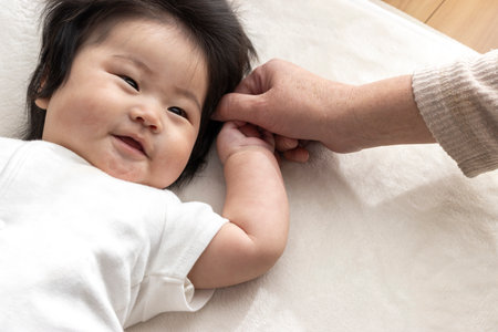 Baby holding hands with grandma (0 years old, 6 months old, Japanese, girl)の写真素材