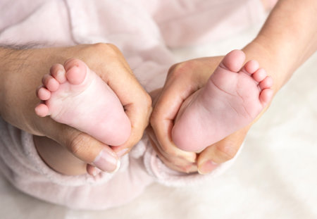 Parents' hands holding the baby's feet (0 years old, 6 months old, Japanese, girl, faceless)の写真素材