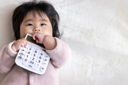 Baby holding a calculator (0 years old, 6 months old, girl, Japanese)の写真素材