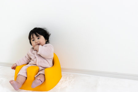 Baby sitting in a baby chair (0 years old, 7 months old, girl, Japanese)の写真素材