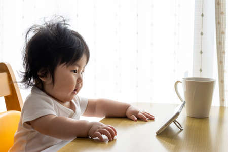 A baby who uses a smartphone. Image of digital native generation (0 years old, 7 months old, girl, Japanese)の写真素材