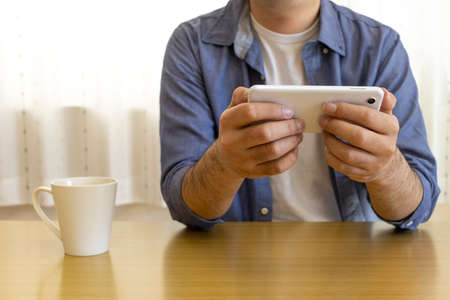 Men sitting in chairs and using smartphones (30s, Japanese, plain clothes)