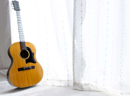 Acoustic guitar under maintenance leaning against the window