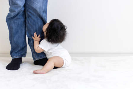 Baby hugging father's feet (0 years old, 8 months old, Japanese, girl)の写真素材