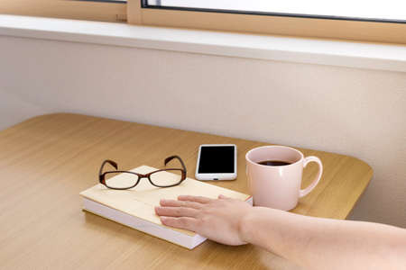 Reading break image. Books, coffee, smartphones, handsの写真素材