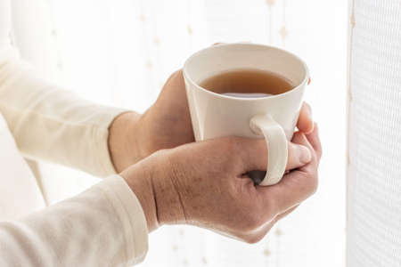 A senior woman holding a warm cup with both hands (Japanese, 60s, elderly)の写真素材