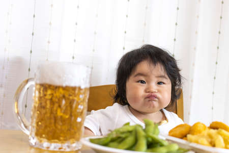Image of baby drinking beer at home table (0 years old, 9 months old, Japanese, girl)の写真素材