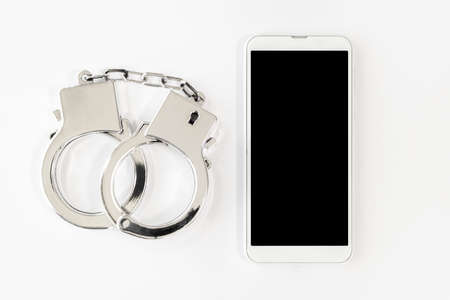 Smartphone and handcuffs. Image of cybercrimeの写真素材