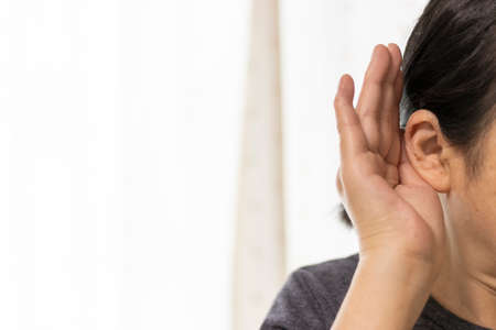 Close up of a senior woman trying to listen with her hand on her ear (60s, Japanese)の写真素材
