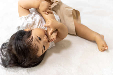 Baby lying down and licking feet (1 year old, Japanese, girl)
