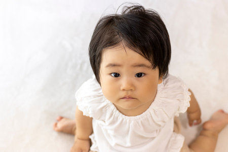 Baby sitting on the carpet and looking up (1 year old, Japanese, girl)の写真素材