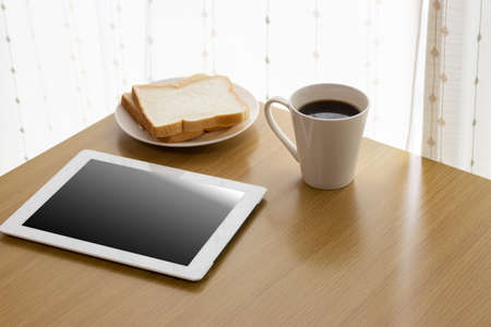 Image of using a tablet device while eating breakfastの写真素材