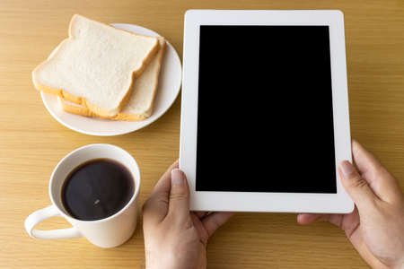 Image of a man's hand using a tablet device while eating breakfastの写真素材