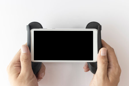 A man's hand holding a smartphone with a gaming grip stand
