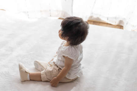 Baby sitting in baby shoes (1 year and 2 months old, girl, Japanese)の写真素材