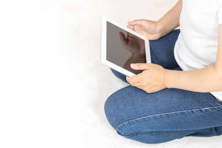 Image of a woman sitting on a carpet and using a tablet device (30s, Japanese, no face)の写真素材