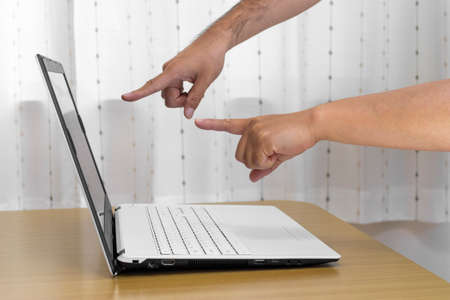 Men's and women's hands pointing at the screen of a laptop computer (Japanese, 30s)の写真素材