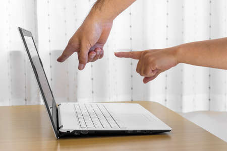 Men's and women's hands pointing at the screen of a laptop computer (Japanese, 30s)の写真素材