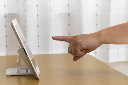 Female hand pointing at the screen of a tablet device (Japanese, 30s)の写真素材