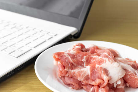 Image of looking up recipes for pork dishes on a laptopの写真素材