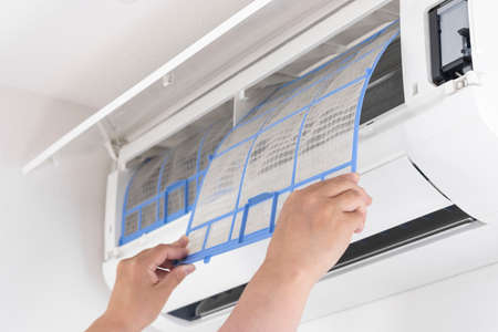 Image of a woman cleaning an air conditioner filterの写真素材