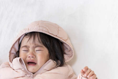 A crying baby wearing a down jacket (1 year and 5 months old, Japanese, girl)の写真素材
