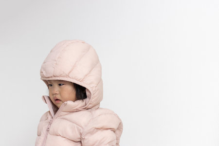 A baby with a sad expression wearing a down jacket (1 year and 5 months old, Japanese, girl)の写真素材