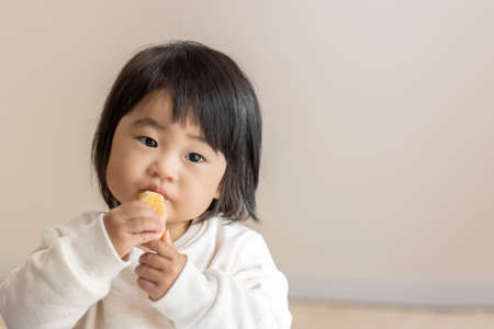Baby eating small bread by herself (1 year and 5 months old, girl, Japanese)の写真素材