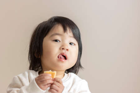 Baby eating small bread by herself (1 year and 5 months old, girl, Japanese)の写真素材