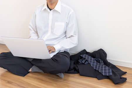 A man who takes off his suit and relaxes and uses a laptopの写真素材