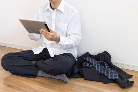 A man who takes off his suit, relaxes and uses a tablet deviceの写真素材