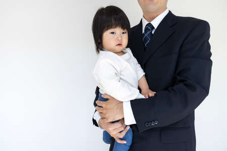Baby (1 year and 6 months old, girl, Japanese) A man in a suit holding a baby (30s, Japanese)の写真素材