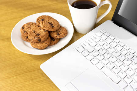 Image of eating cookies during breaks and using a laptop computerの写真素材