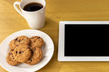 Image of eating cookies during breaks and using a tablet deviceの写真素材