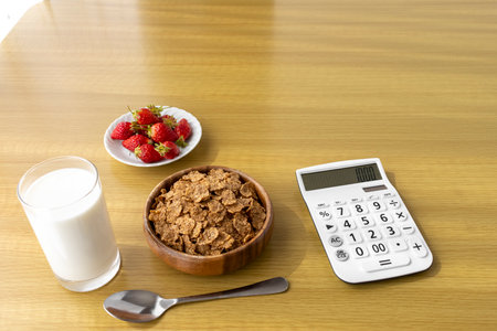 Calculator and breakfast (flakes, strawberries, milk). Image of food expenses