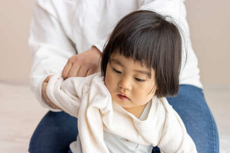 Changing clothes for a baby (1 year and 8 months old, girl, Japanese)の写真素材