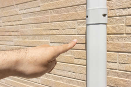 Man's hand checking the hose cover of the air conditionerの写真素材
