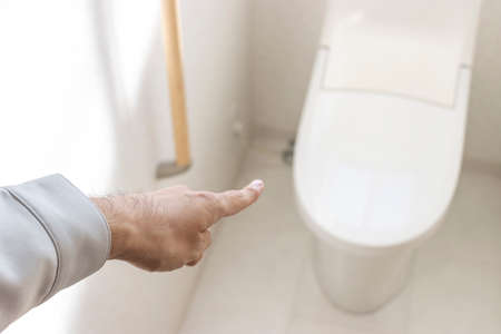 A man's hand checking a Western-style toiletの写真素材