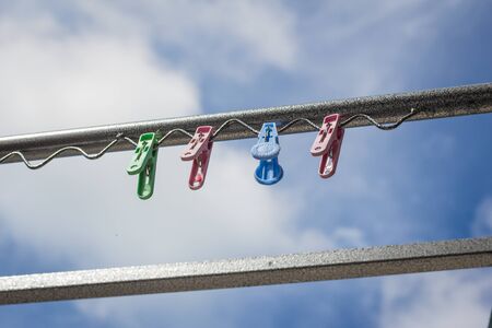 Plastic clothespin on a clothesline and in the daytime sky.