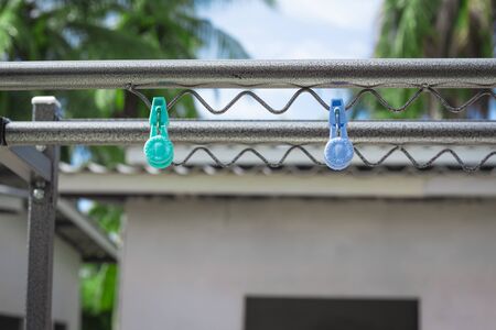 Plastic clothespin on a clothesline and in the daytime sky.
