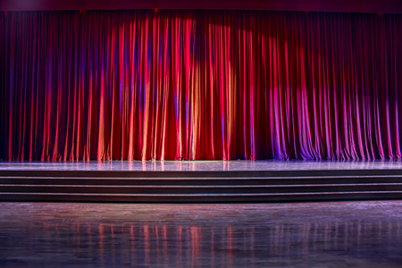 Red curtains and the stage parquet with stairs in theater with colorful lighting.の写真素材