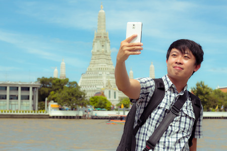 Man is standing selfie on the river in Thailand. Tourists holding mobile phone to take pictures...