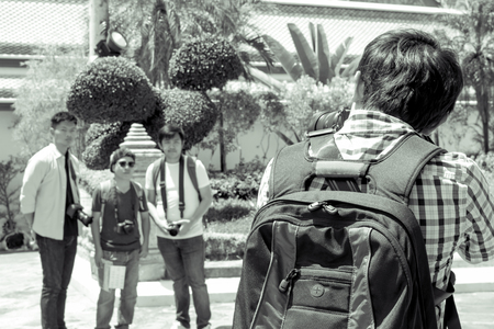 Black and white male tourist holding a camera and taking pictures friends.
