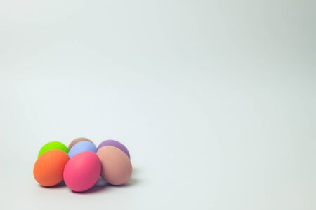 Easter eggs multicolor with white background. Easter eggs, orange, pink, purple, green, blue and brown pile in the  left corner on a white background. Eggs was coloring in the festival of Easter.の写真素材