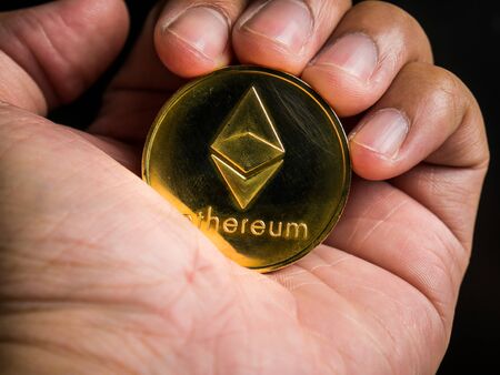 Business male hand is holding gold ethereum coin. Business value cryptocurrency are expensive.