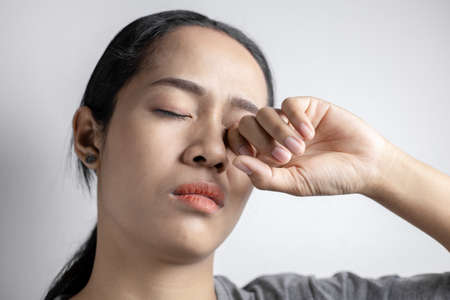 Young woman with of eye pain on a gray background. Asian  woman is suffering of eye pain. Woman suffering from strong eye pain.の写真素材