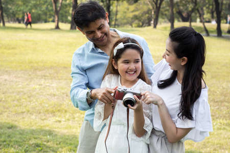 Asian families watching pictures from their cameras at the park with happy.の写真素材